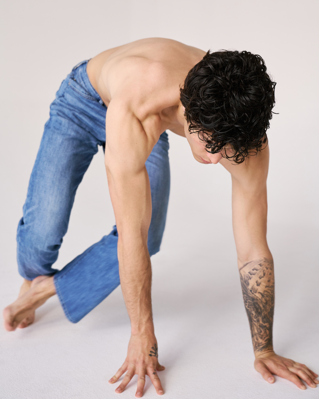 Young man in blue jeans with hands on the ground