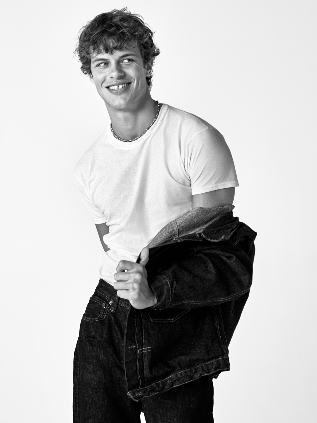Black and white image of a young man taking off jacket