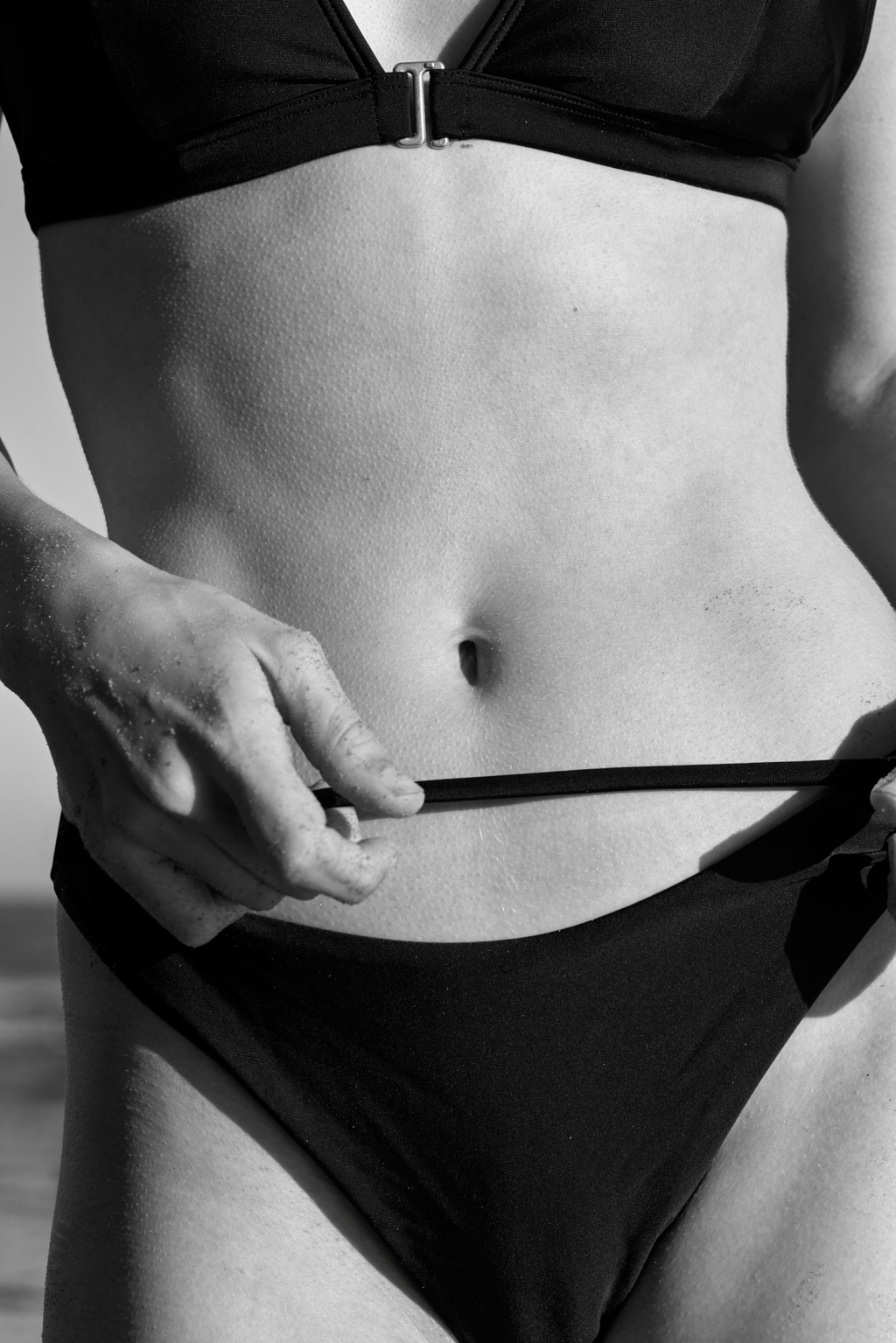 Black and white detail of a young woman's torso in a bikini