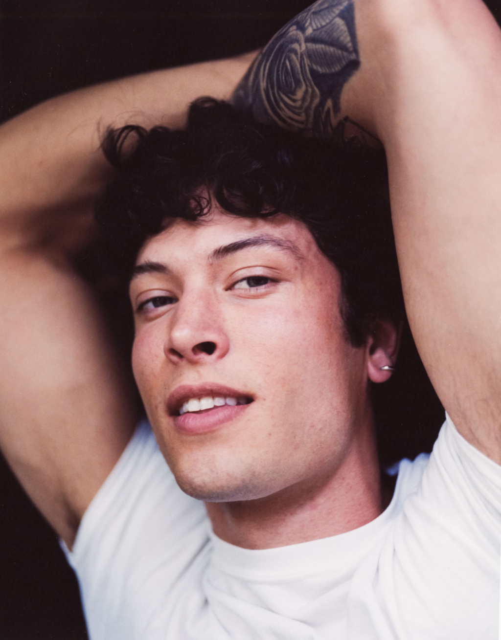Portrait of young man lying down with arms behind his head