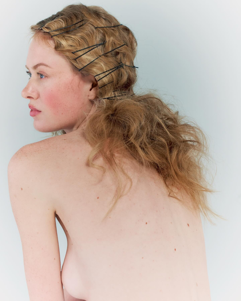 Young woman with curled blonde hair facing away from camera