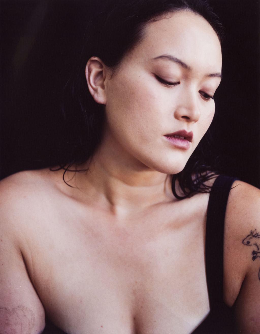 Portrait of a young woman with tattoos looking down